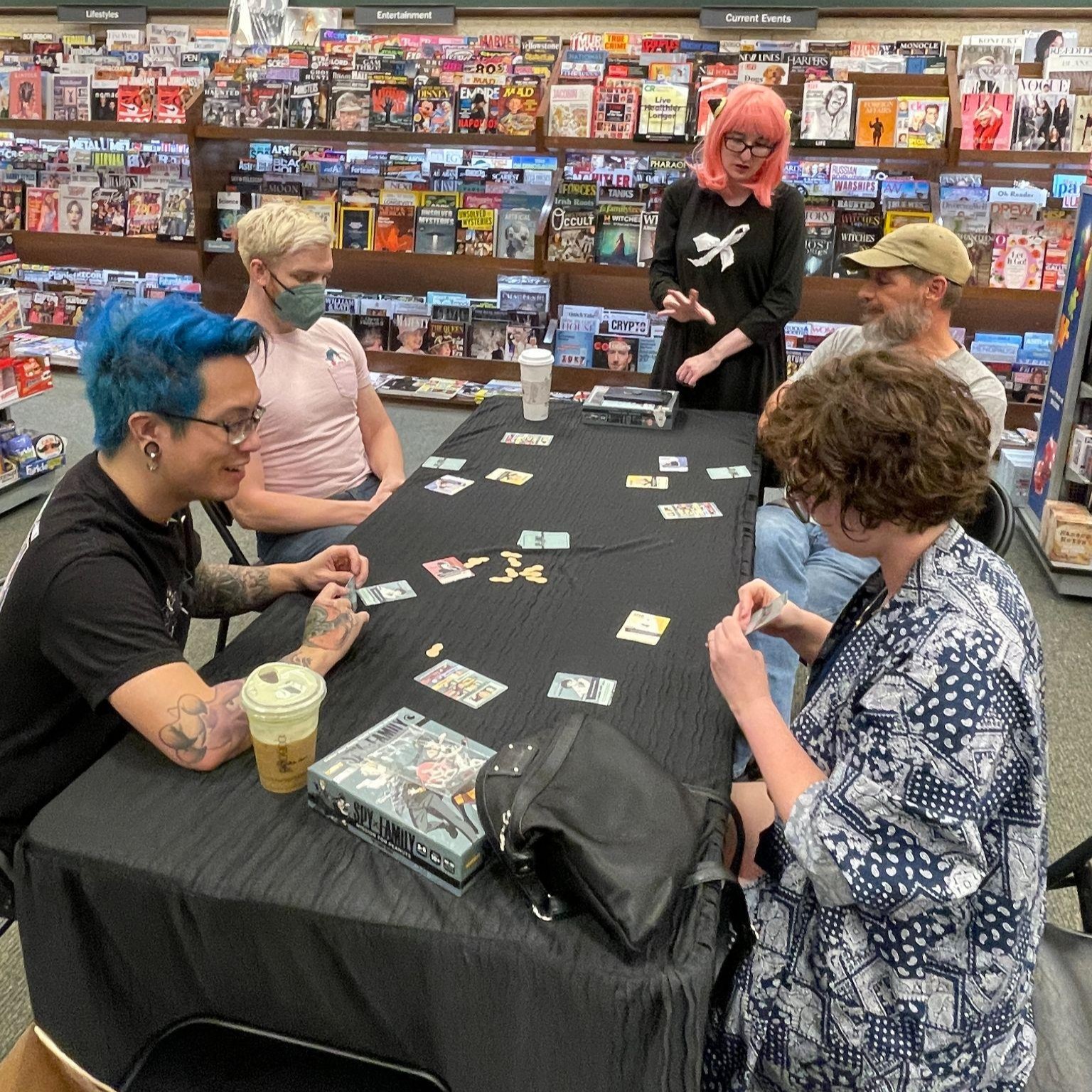 Attendees playing Spy x Family: Mission for Peanuts at the demo table, with an Anya cosplayer looking on